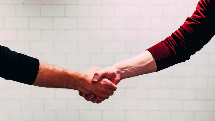 Image of a handshake with a white brick wall background.