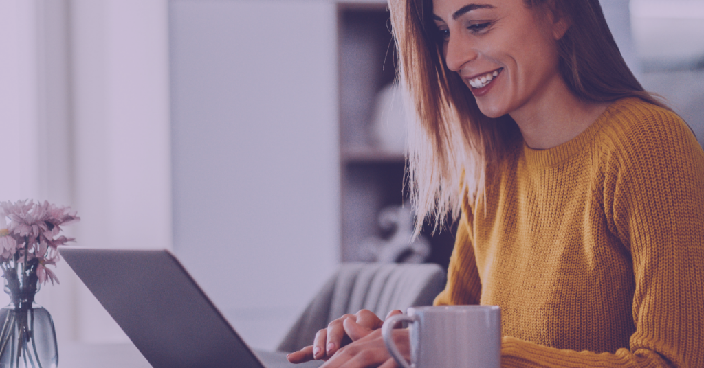 An image of a woman smiling while working on the computer.