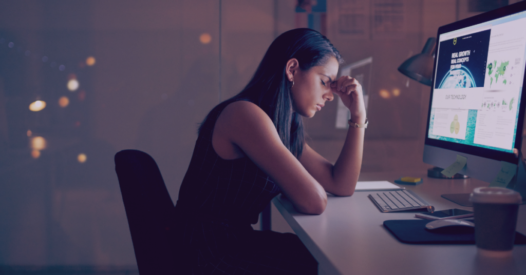 An image of a woman sitting at a computer looking stressed out.